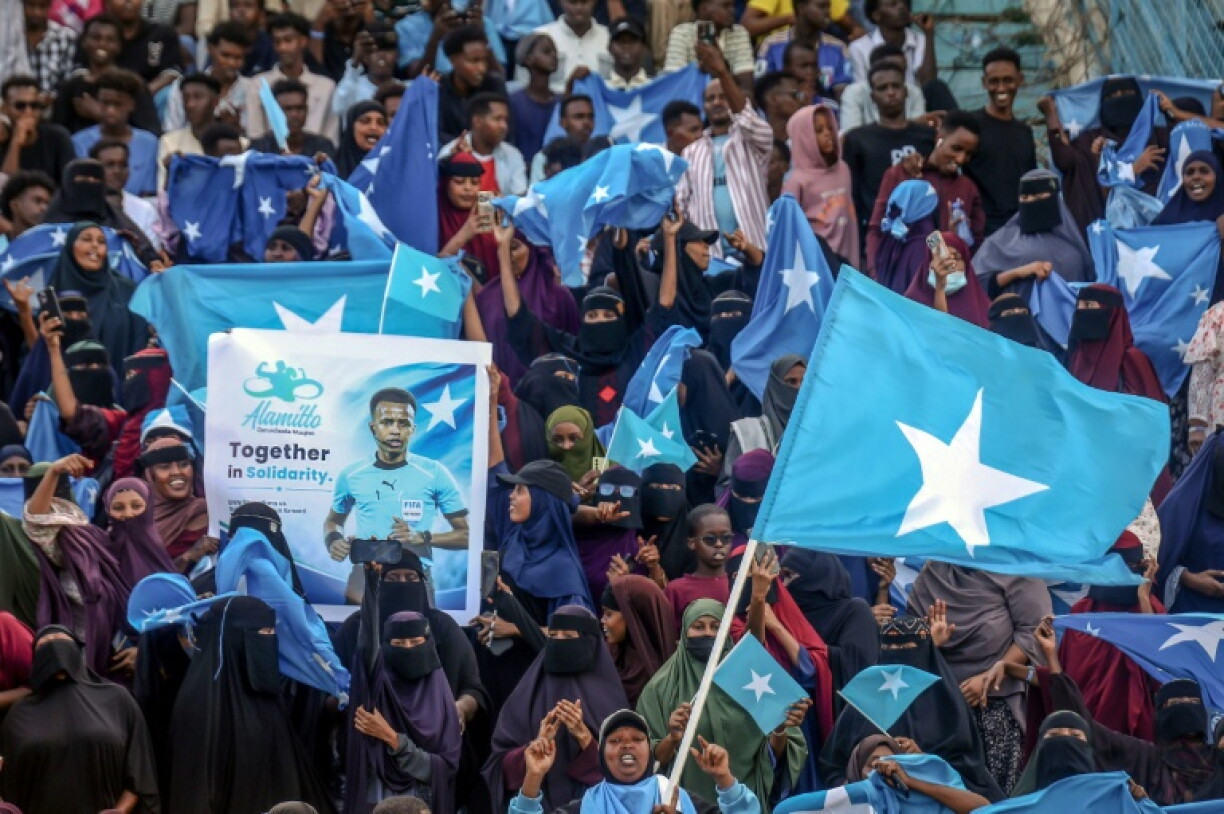 Des supporters de l'arbitre somalien Omar Artan tiennent des drapeaux et des banderoles pour l'accueillir avant un match de football de solidarité organisé à Mogadiscio, à l'occasion de son retour en Somalie, le 10 juin 2026