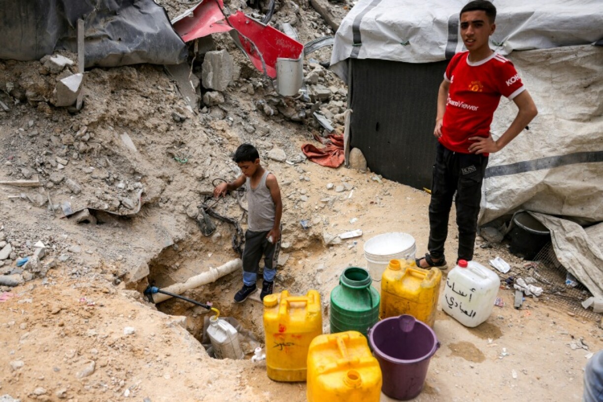 A boy fills containers from the remaining water still left in underground pipes, in Beit Lahia, northern Gaza