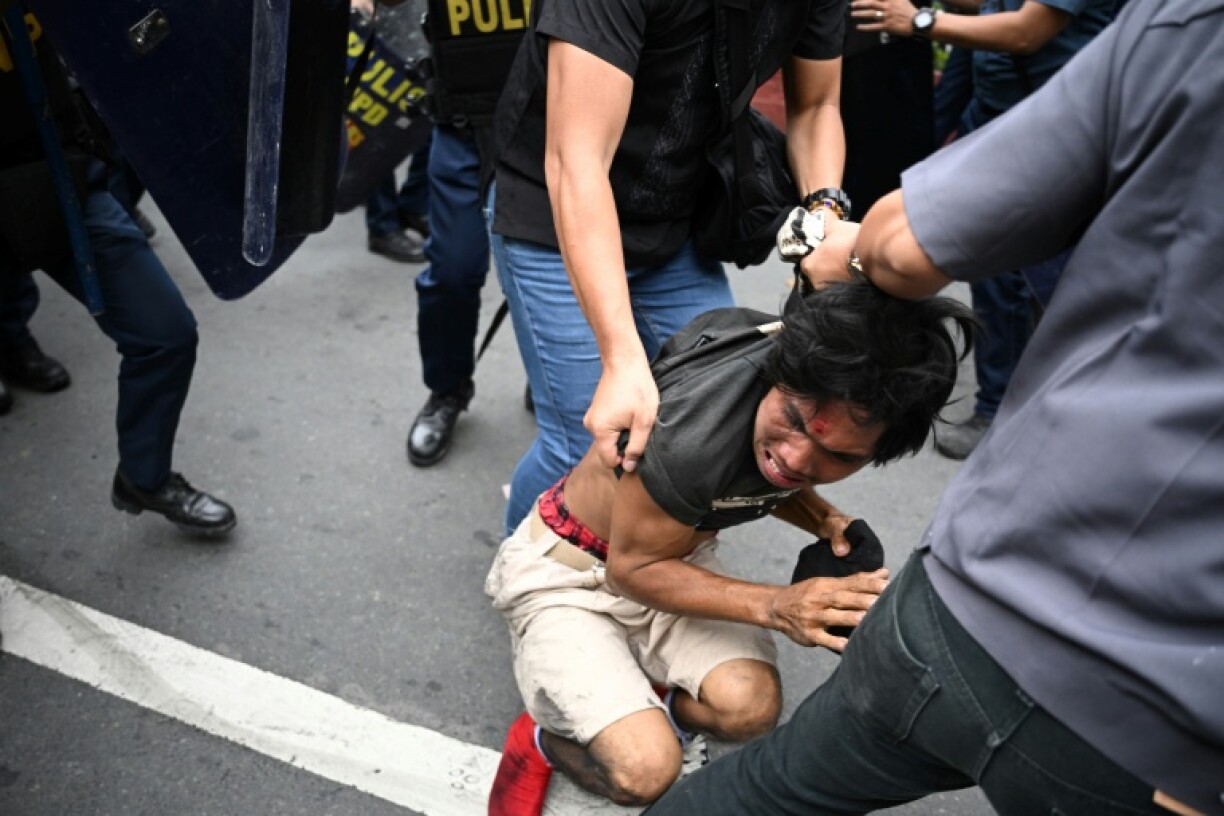 A protester suspected of clashing with police is arrested near the presidential palace in Manila on Sunday