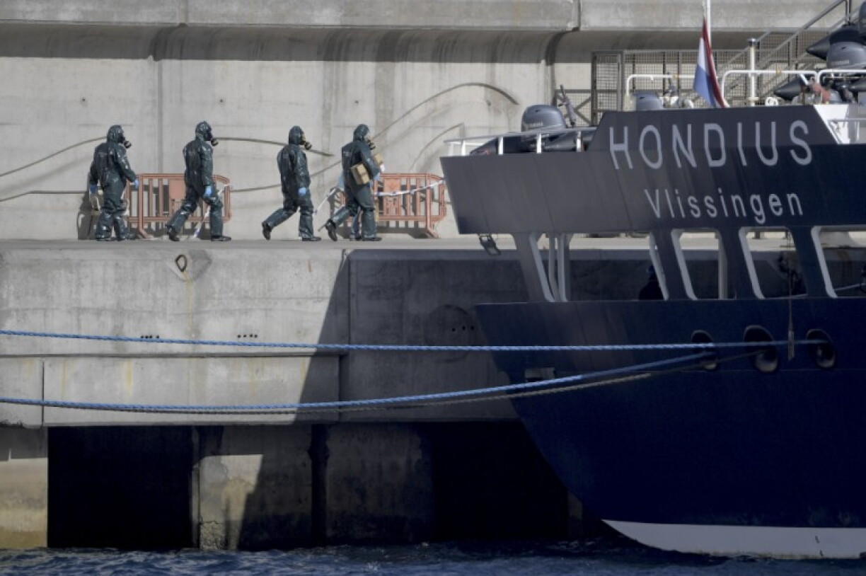 Persons wearing protective suits walk toward the hantavirus-stricken cruise ship MV Hondius docked in the port of Granadilla de Abona on the island of Tenerife in Spain's Canary Islands on May 11, 2026.