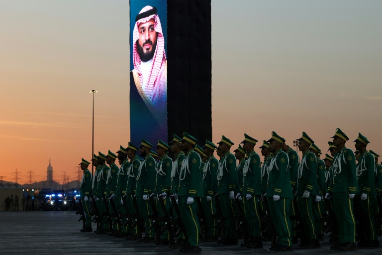 Saudi security forces stand at attention beneath a portrait of Saudi Arabia's Crown Prince, Mohammed bin Salman, during a military parade as pilgrims arrive for the annual Hajj pilgrimage