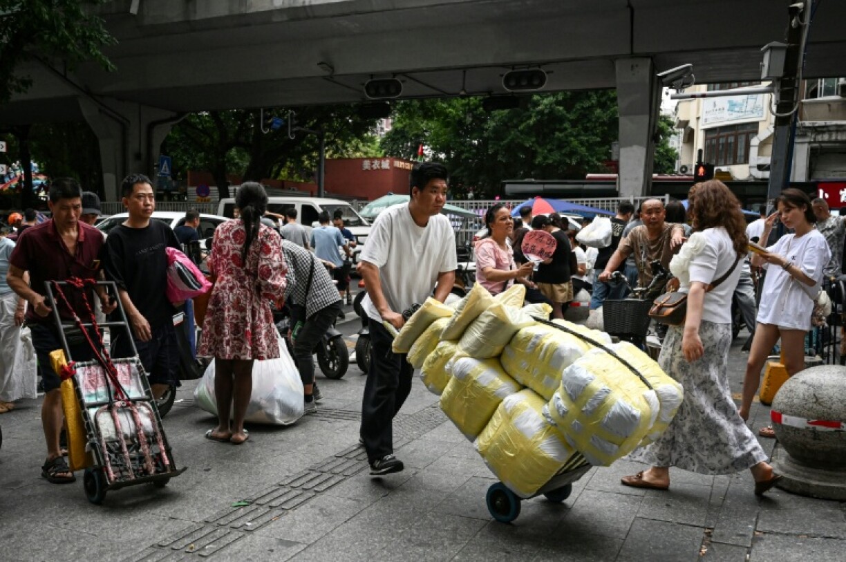 Un homme transportant des ballots de vêtements vers un marché de gros de Canton, en Chine, le 16 avril 2026