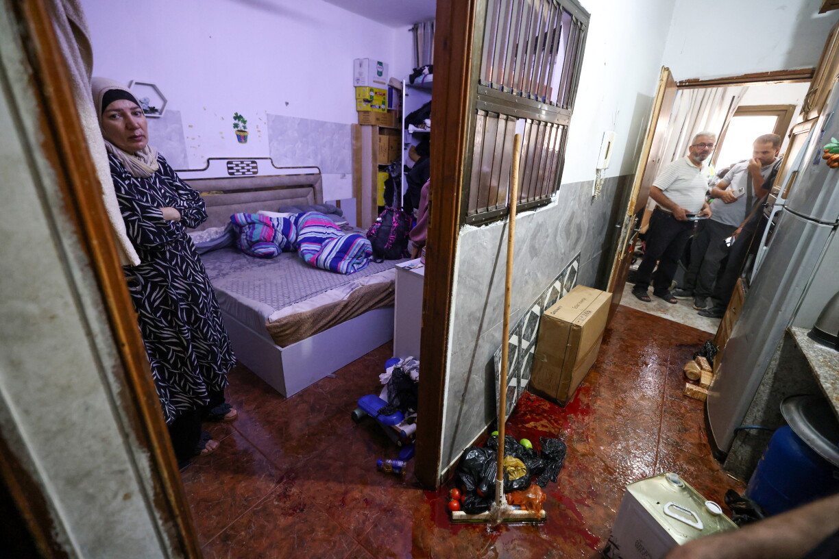 Suad (à gauche), l'épouse de Fathi Zidan Hazem, âgé de 58 ans, tué par l'armée israélienne alors qu'elle tentait de l'arrêter, se tient à la porte de la chambre, près d'une mare de sang, dans leur domicile de la ville de Jénine, au nord de la Cisjordanie palestinienne occupée par Israël, le 21 août 2026.