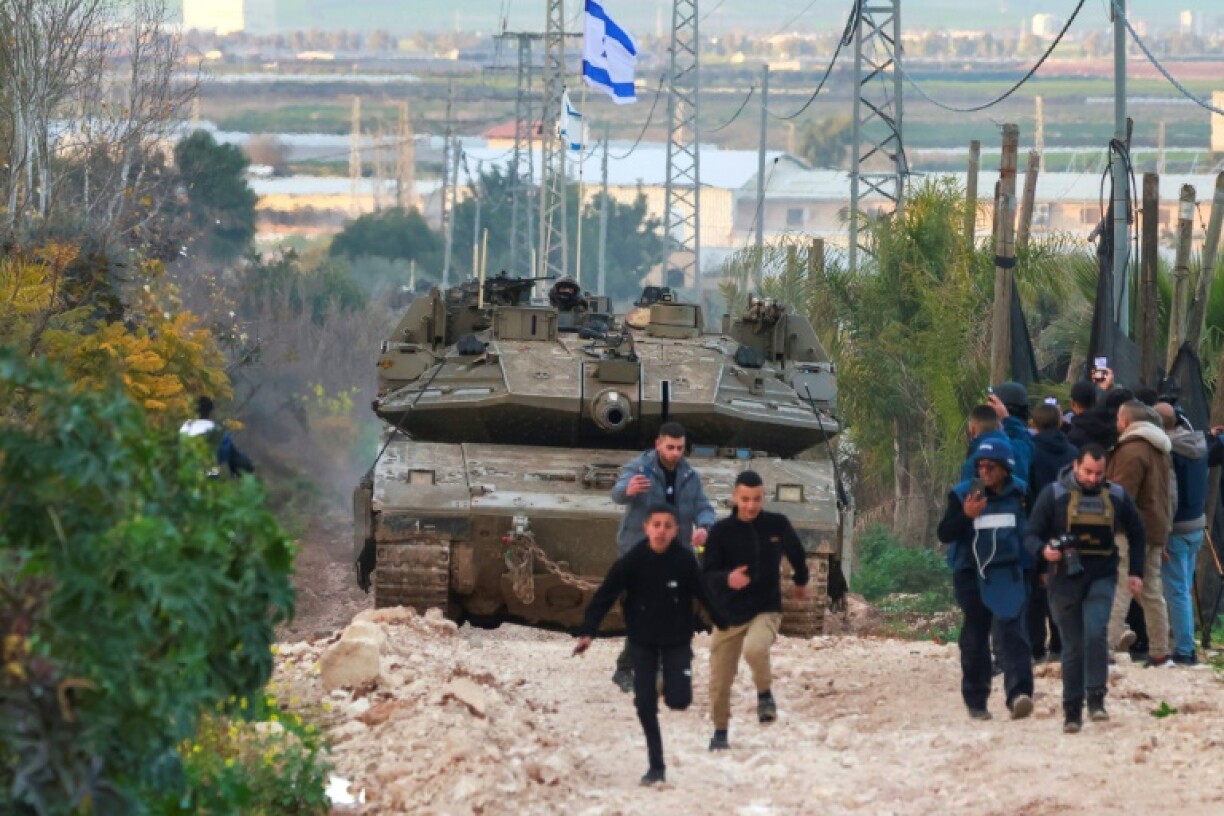 Palestinian children and journalists disperse as Israeli tanks enter the Jenin camp for Palestinian refugees in the occupied West Bank, on February 23, 2025