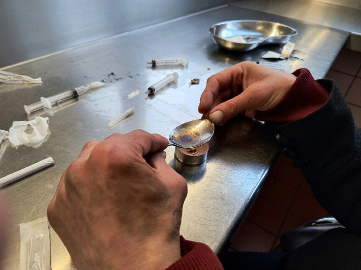 A woman heats heroin into a solution using a spoon and a tea candle