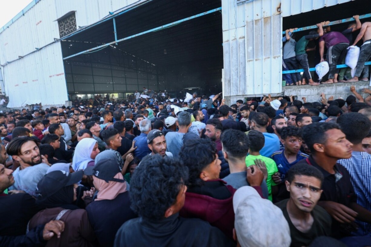 Palestinians ferry bags of food aid as they storm a World Food Programme warehouse in Deir el-Balah in the central Gaza Strip on May 28, 2025