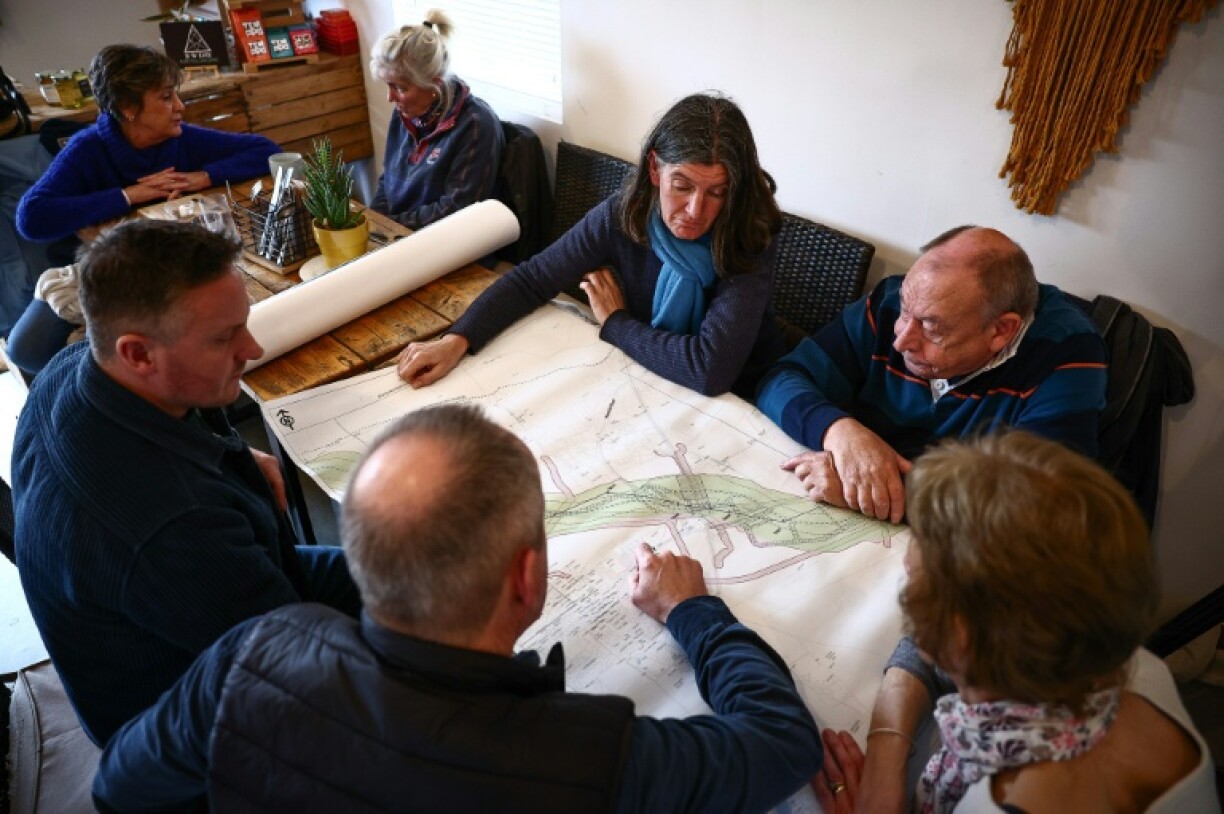 Rosie Pearson speaks with other local residents as they look at a National Grid statutory consultation map outlining proposed plans for a new electricity pylon route in Ardleigh, eastern England