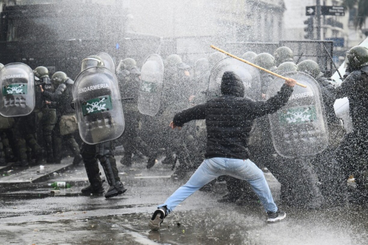 Un manifestant tente de frapper des policiers avec un bâton lors des manifestations devant le parlement argentin, à Buenos Aires le 12 juin 2024