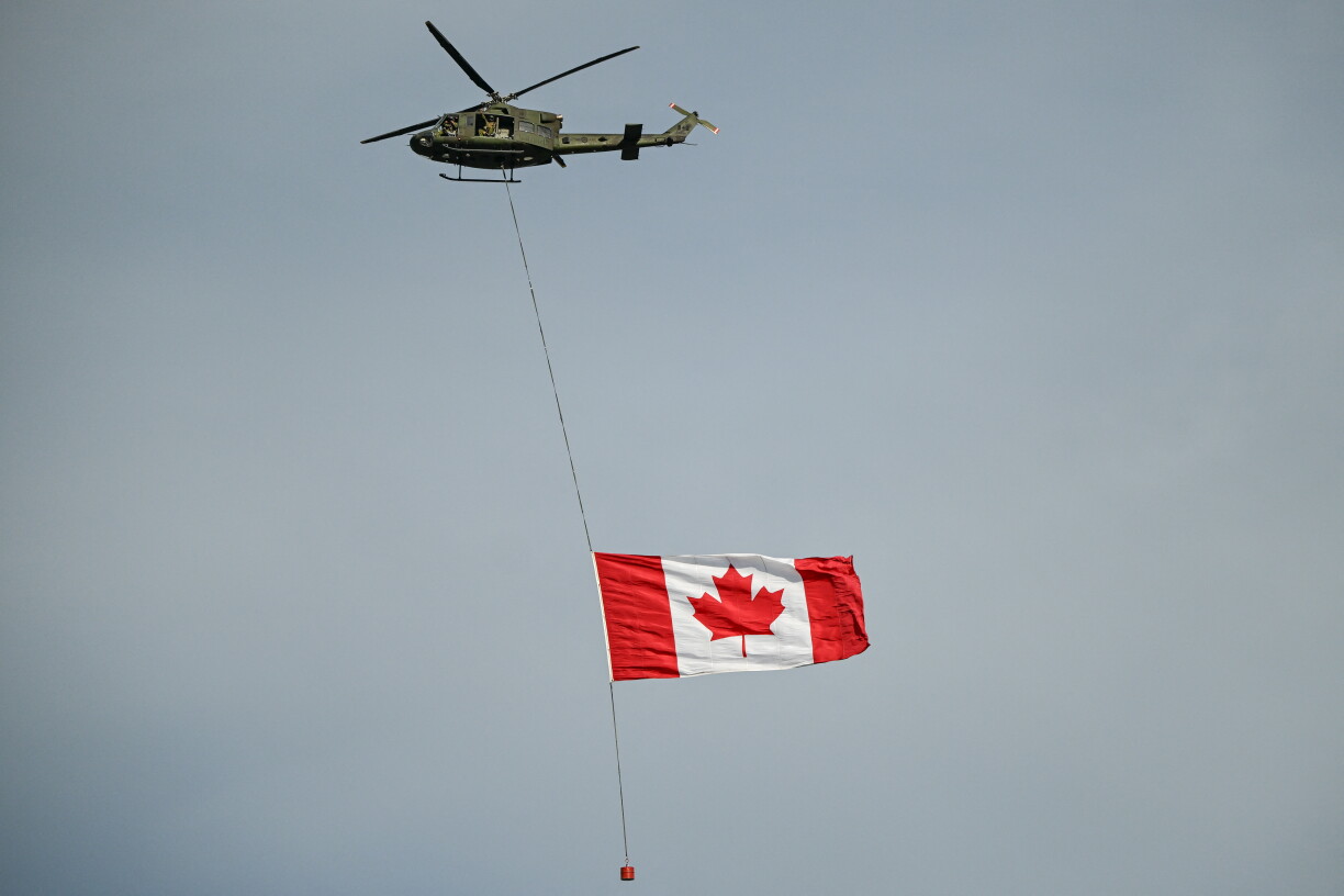 En Helikopter vun der kanadescher Arméi transportéiert e grousse kanadesche Fändel wärend der 2025 Calgary Stampede.