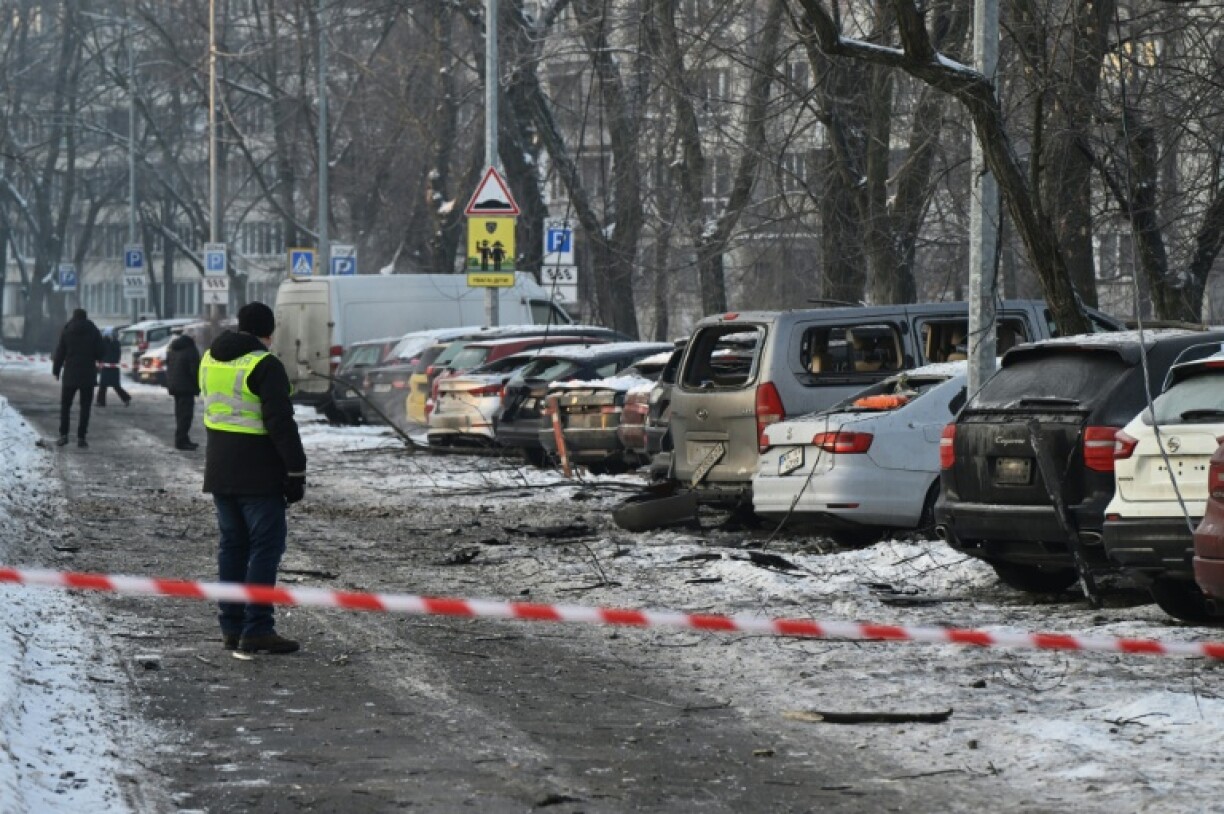 Des habitants devant des voitures endommagées sur un site où des débris de drones russes sont tombés durant une attaque arérienne massive russe, à Kiev en Ukraine le 20 janvier 2026