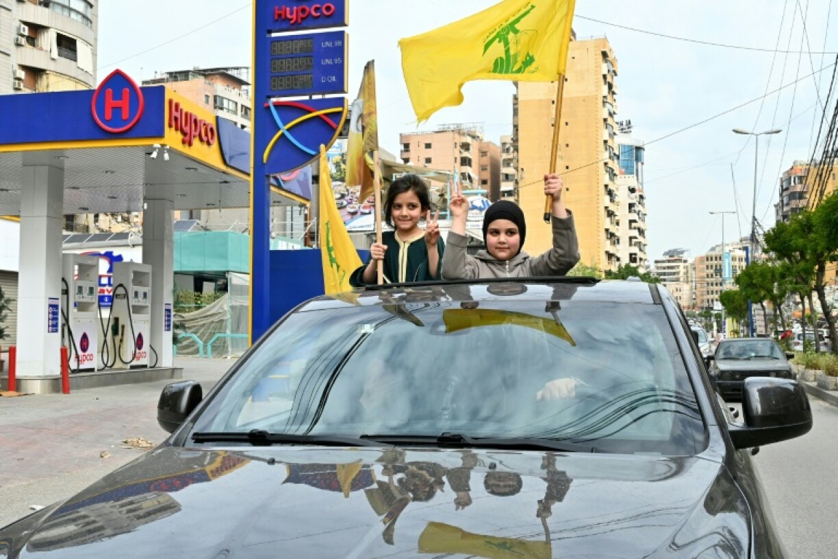 Des fillettes agitent des drapeaux du Hezbollah tandis que des déplacés rentrent dans un quartier de la banlieue sud de Beyrouth après l’entrée en vigueur d’un cessez-le-feu avec Israël, le 17 avril 2026
