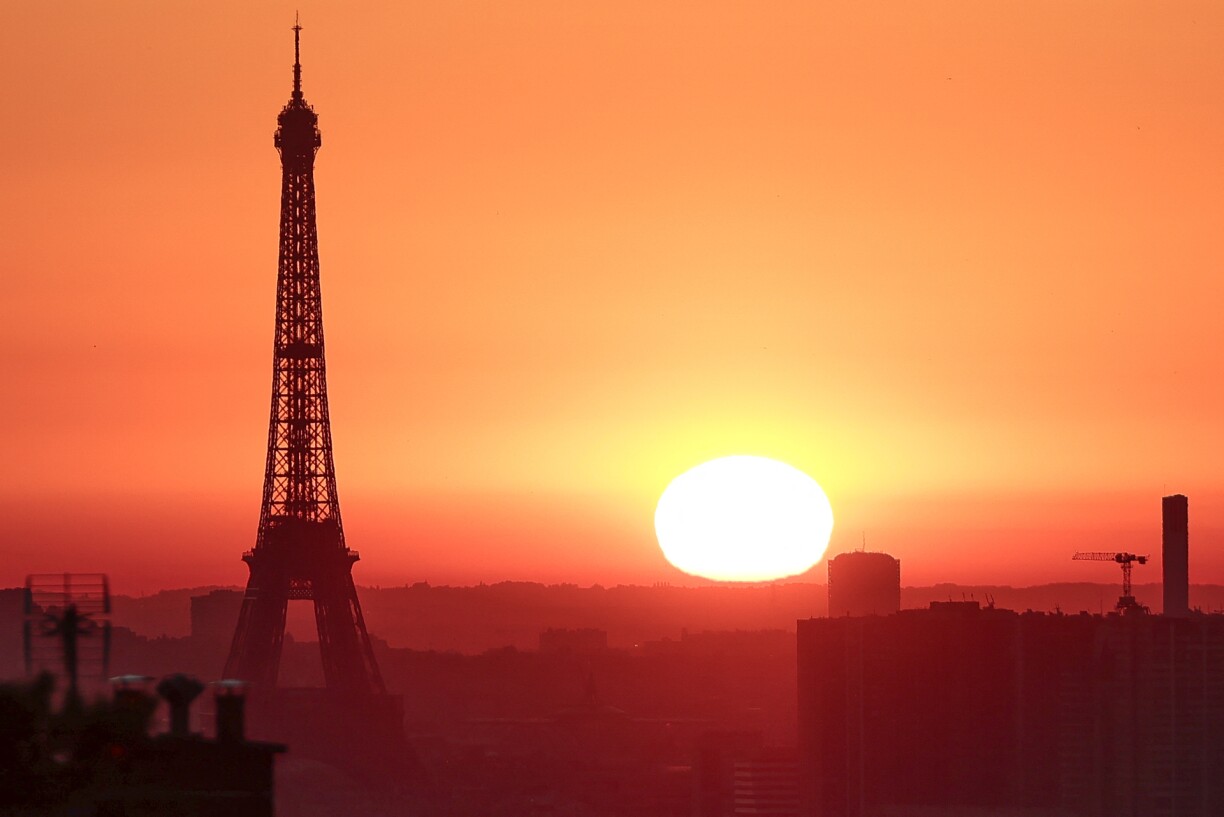 The sun rises by the Eiffel Tower in Paris on July 1, 2025, as the city is on red alert for high temperatures, with the top of the Eiffel Tower shut, polluting traffic banned and speed restrictions in place as a searing heatwave gripped Europe.