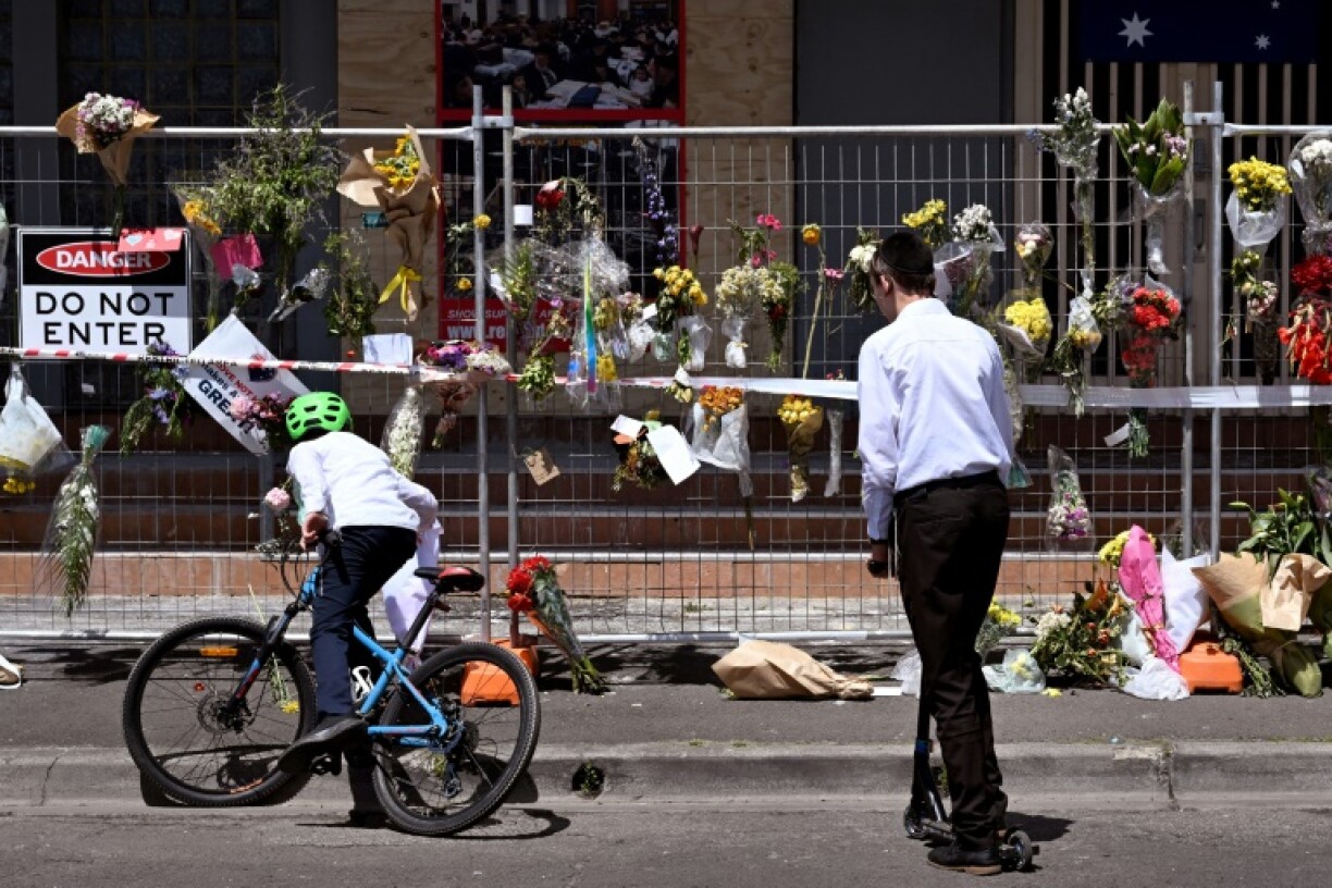 Children from the local Jewish community look at the tributes left outside the torched Adass Israel Synagogue in Melbourne on December 10, 2024