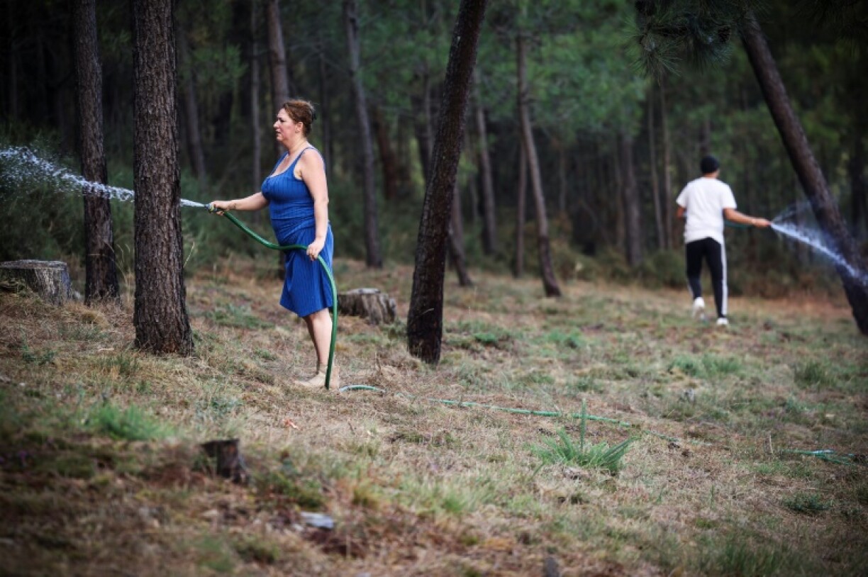 Residents spray water as they try to protect their house from a wildfire in Gondomar, northern Portugal