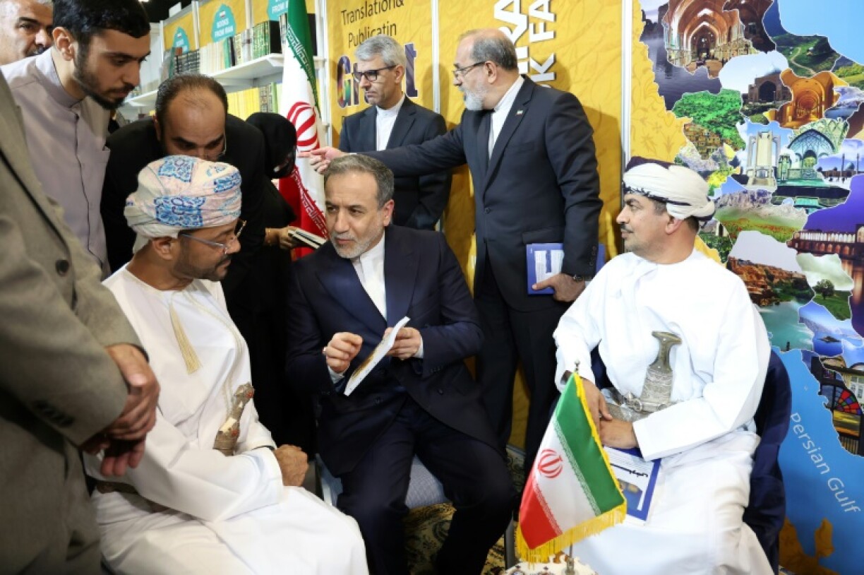 Iran's top diplomat Abbas Araghchi (C) speaks to Omani Foreign Minister Badr Albusaidi (L) at a book signing in Muscat