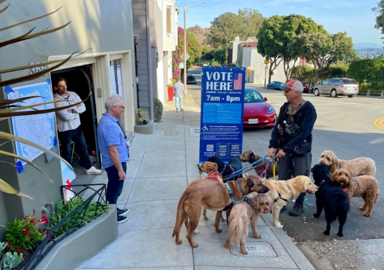 Un promeneur de chiens discute le 5 novembre 2024 avec les agents électoraux d'un bureau de vote installé dans un garage, une pratique courante à San Francisco