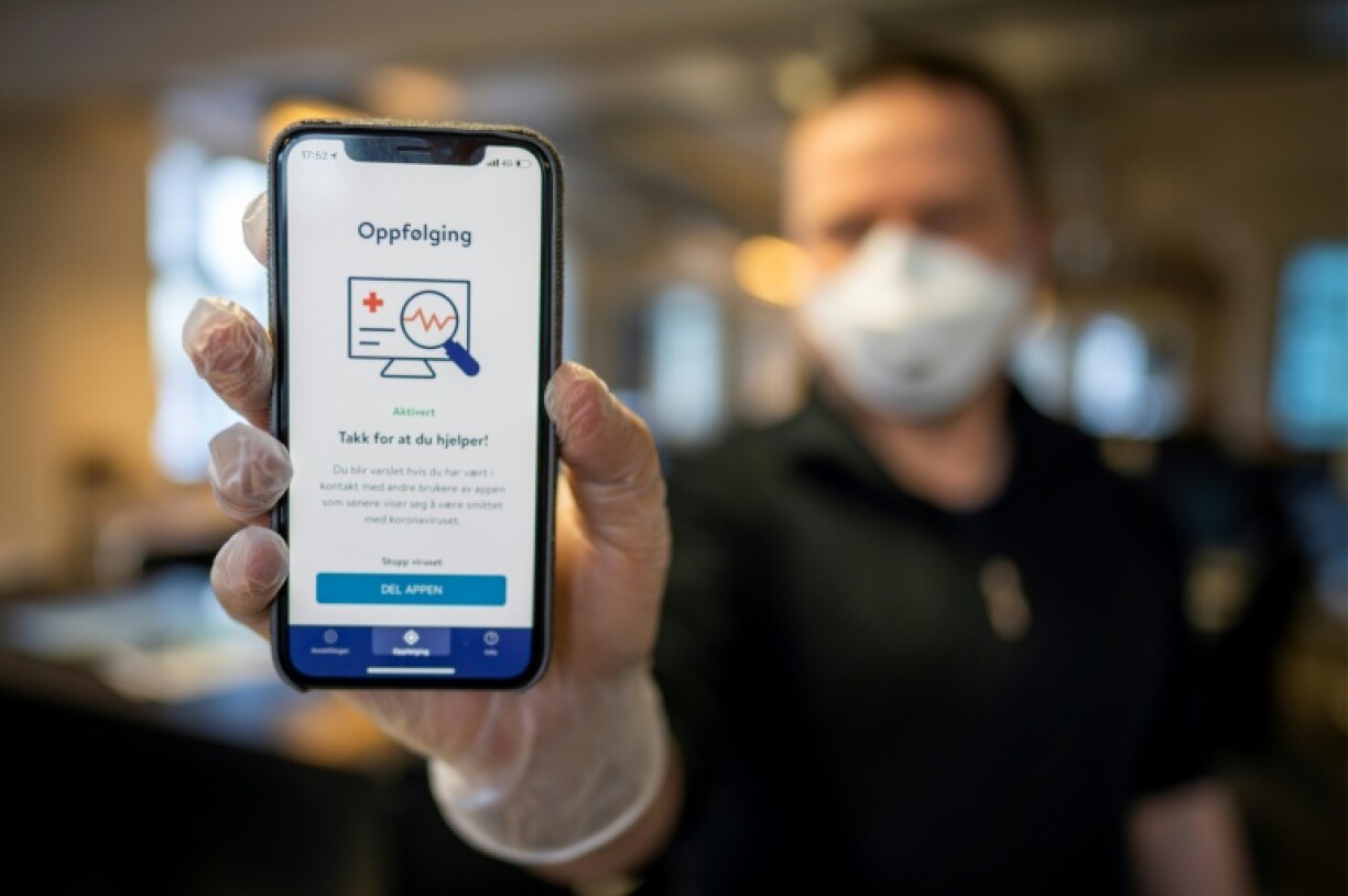 Un homme tient un smartphone montrant une application de traçage, le 17 avril 2020 à Oslo.