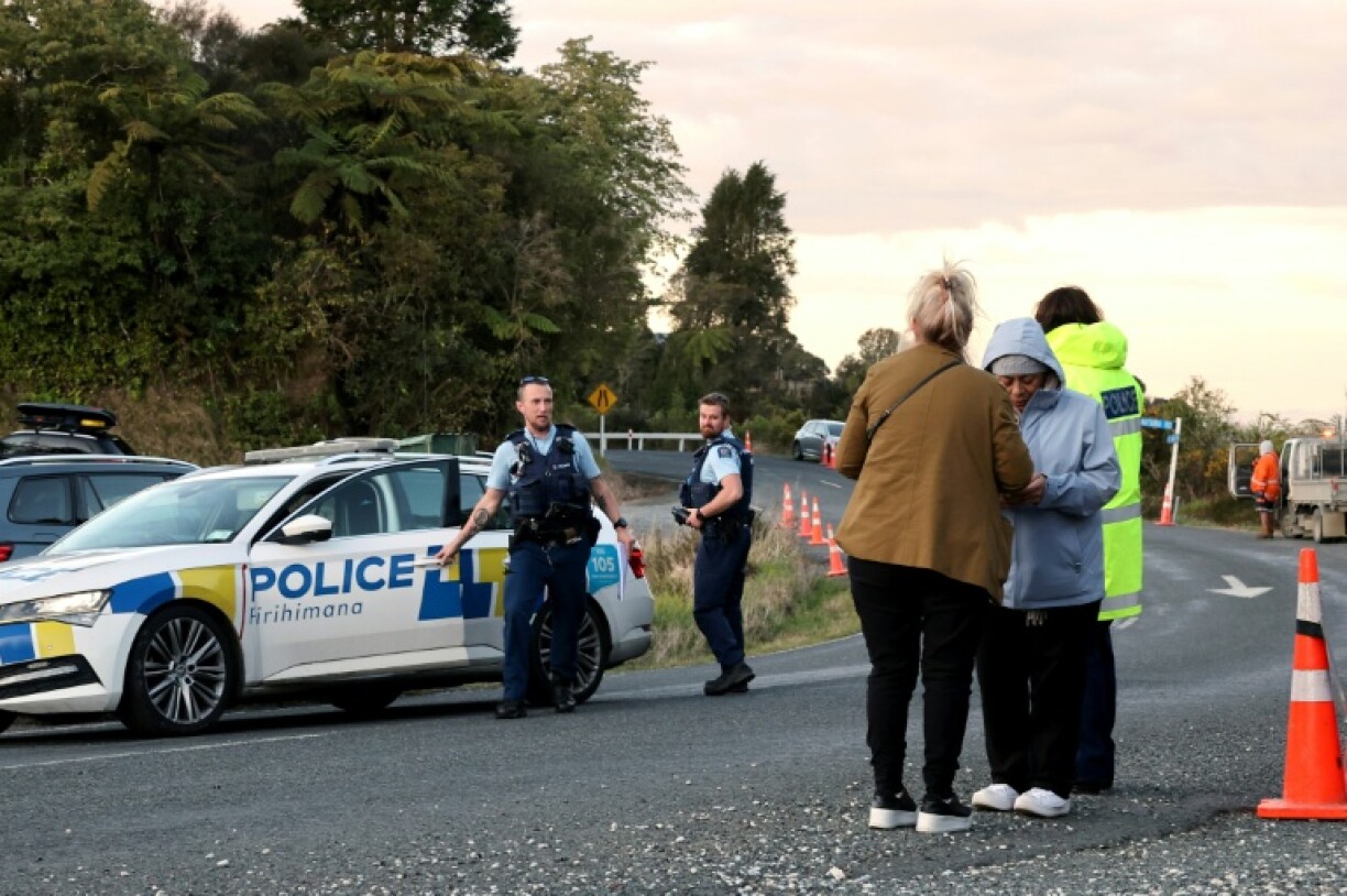 Police officers and locals stand near a roadblock where a police shootout occurred near the town of Piopio, located in New Zealand’s Waikato region on September 8, 2025