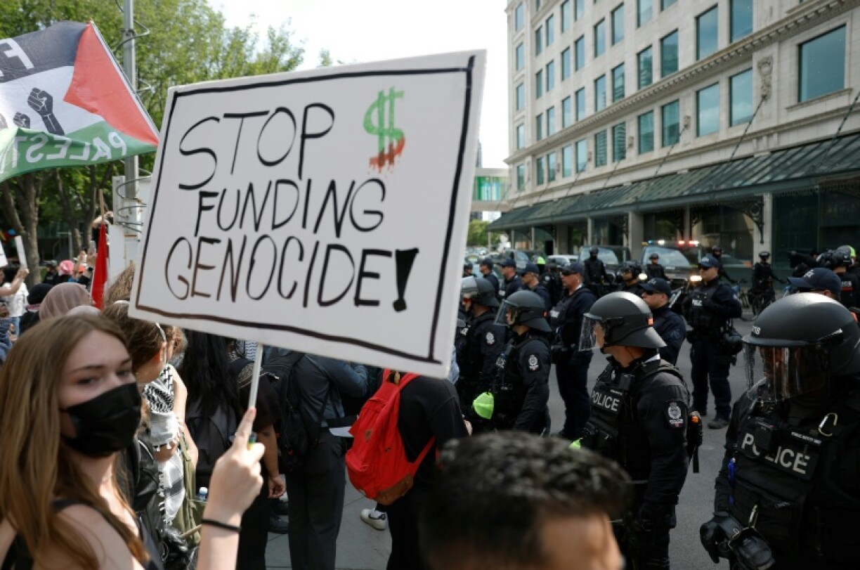 A protester holds a sign during a demonstration in front of Calgary City Hall on June 15, 2025, as world leaders converge in Canada for the G7 Summit