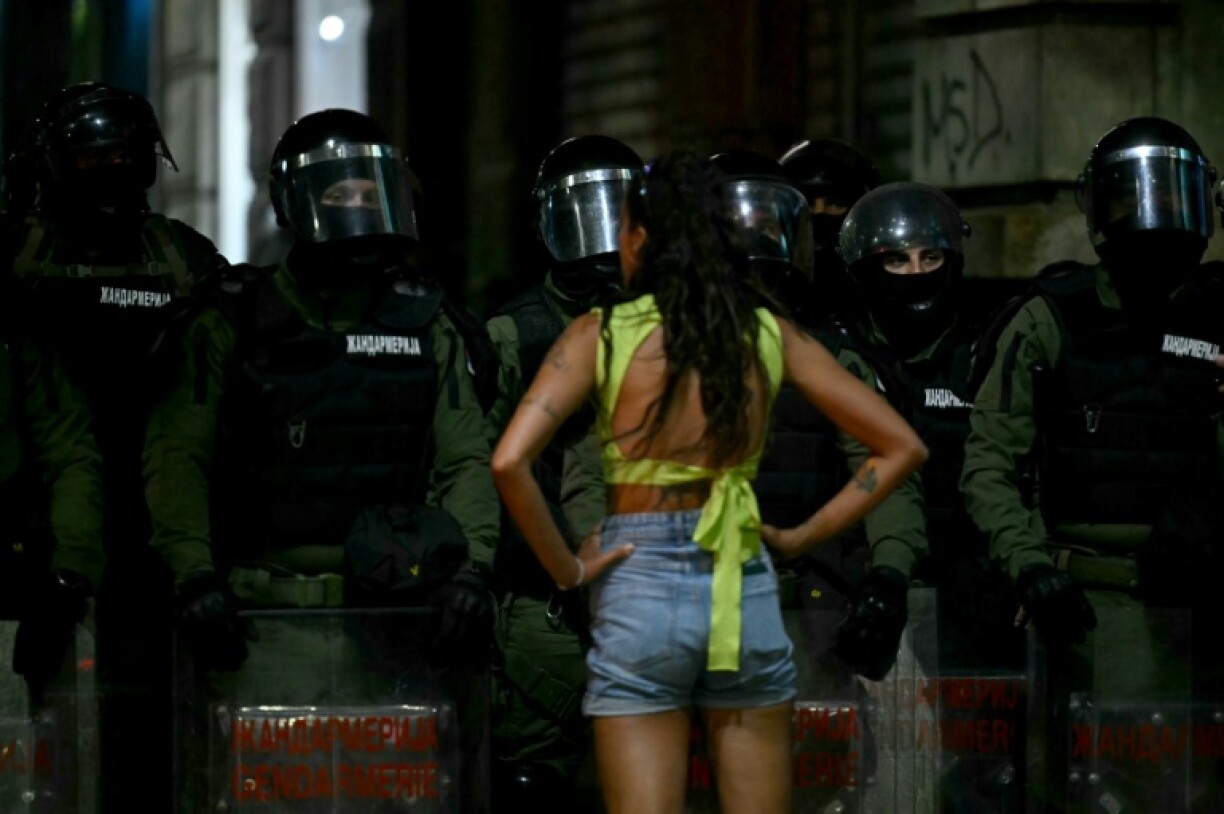 A protestor faces Serbian Riot Police as tens of thousands of protesters gather in central Belgrade