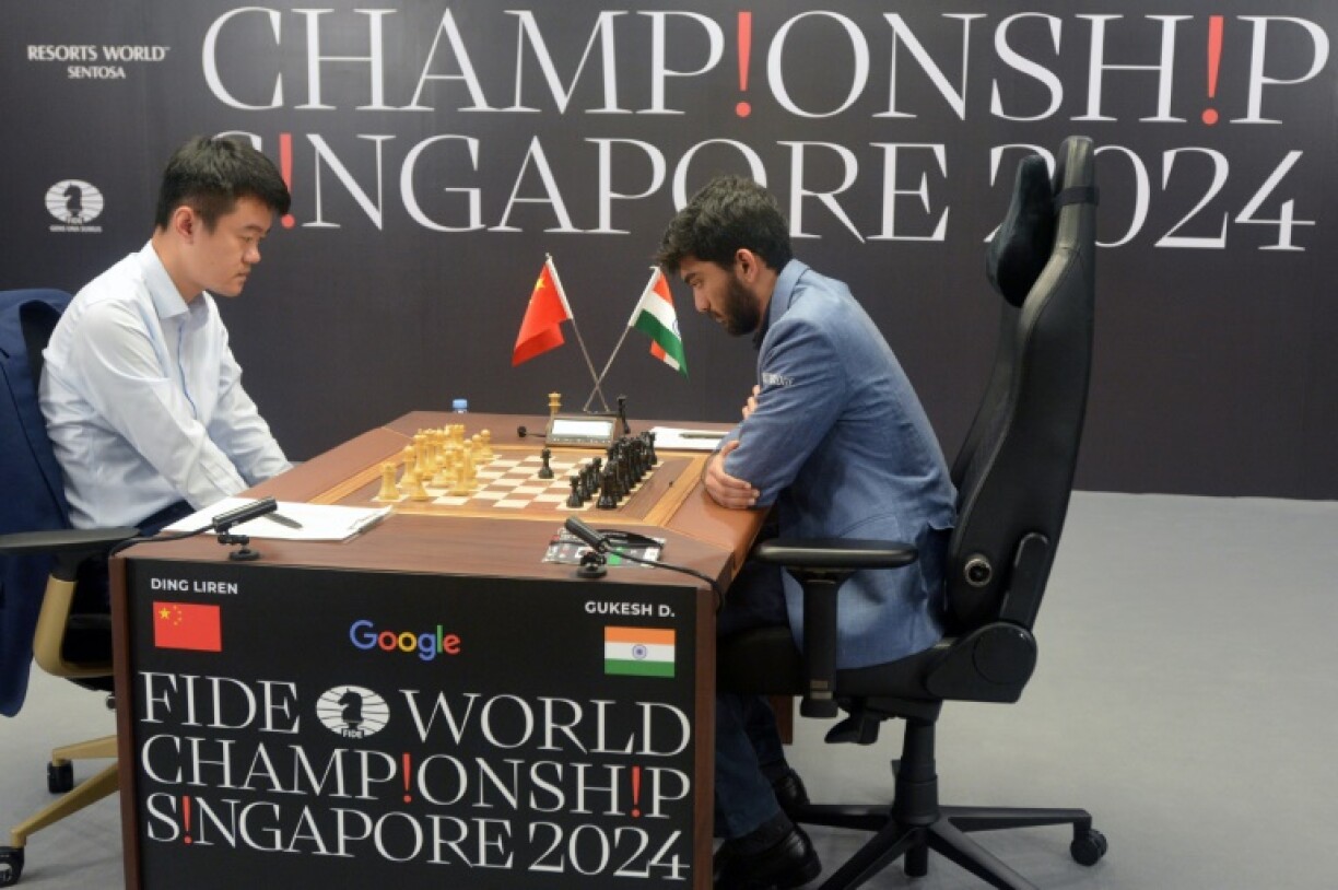 China's chess grandmaster Ding Liren (L) and India's grandmaster Gukesh Dommaraju (R) compete in the final game of the 2024 FIDE World Championship in Singapore