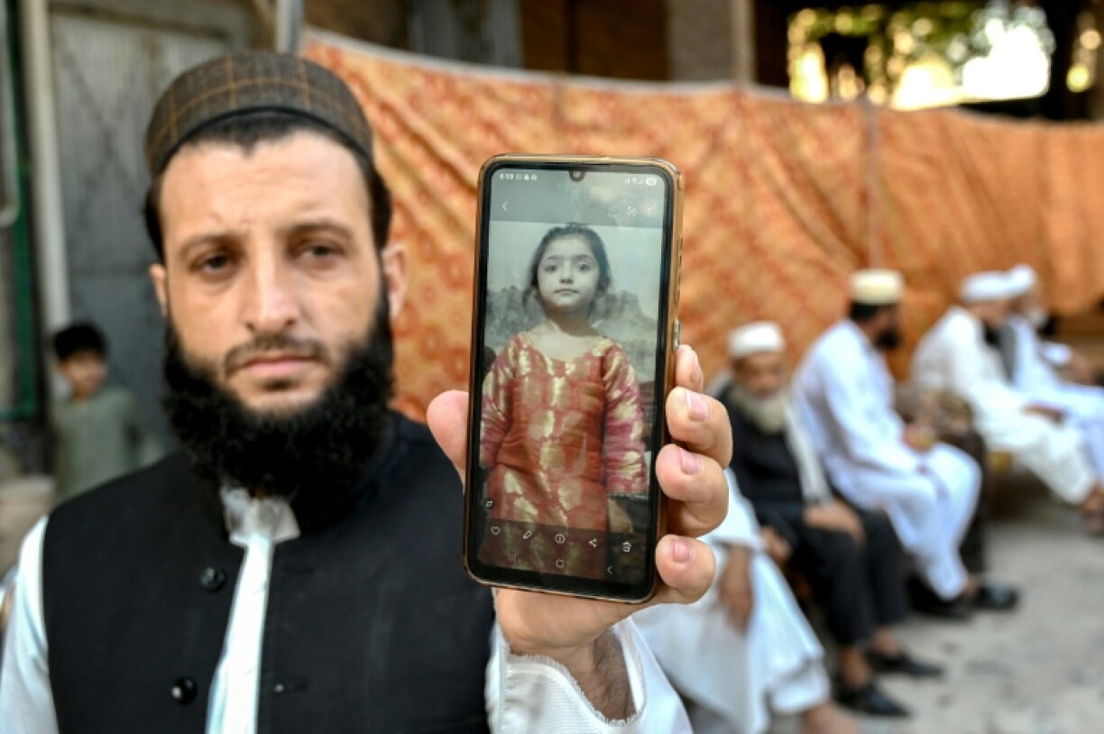 A father shows a photograph of his daughter, who was killed when her school's roof collapsed in Peshawar