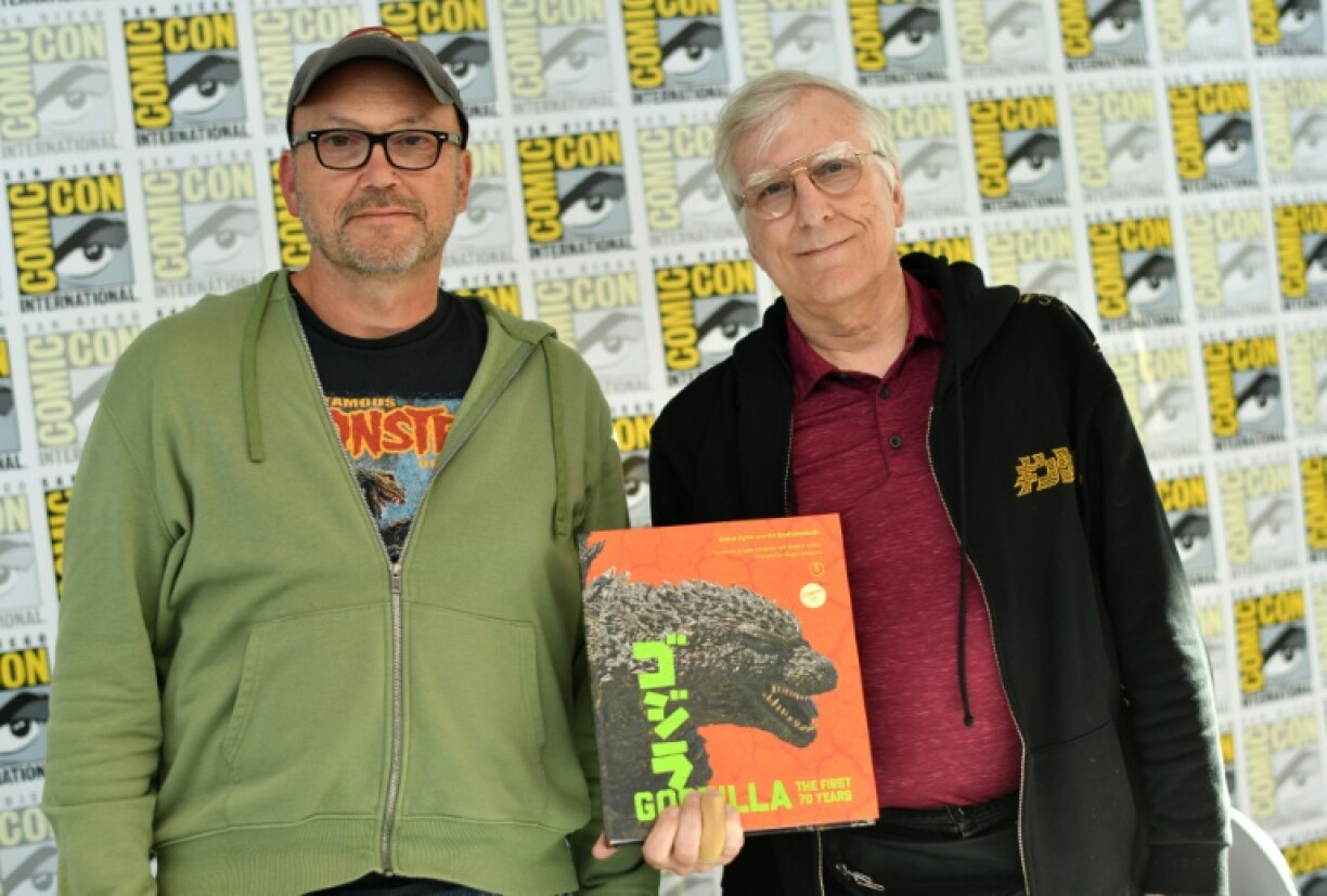 Les auteurs Steve Ryfle (gauche) and Ed Godziszewski (droite) posent avec une copie de leur livre sur les 70 ans de Godzilla