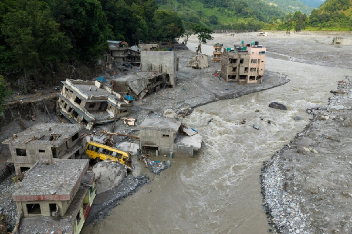 A torrent of muddy water surges past houses in the aftermath of flash floods in Nepal's Nuwakot district on August 29, 2026