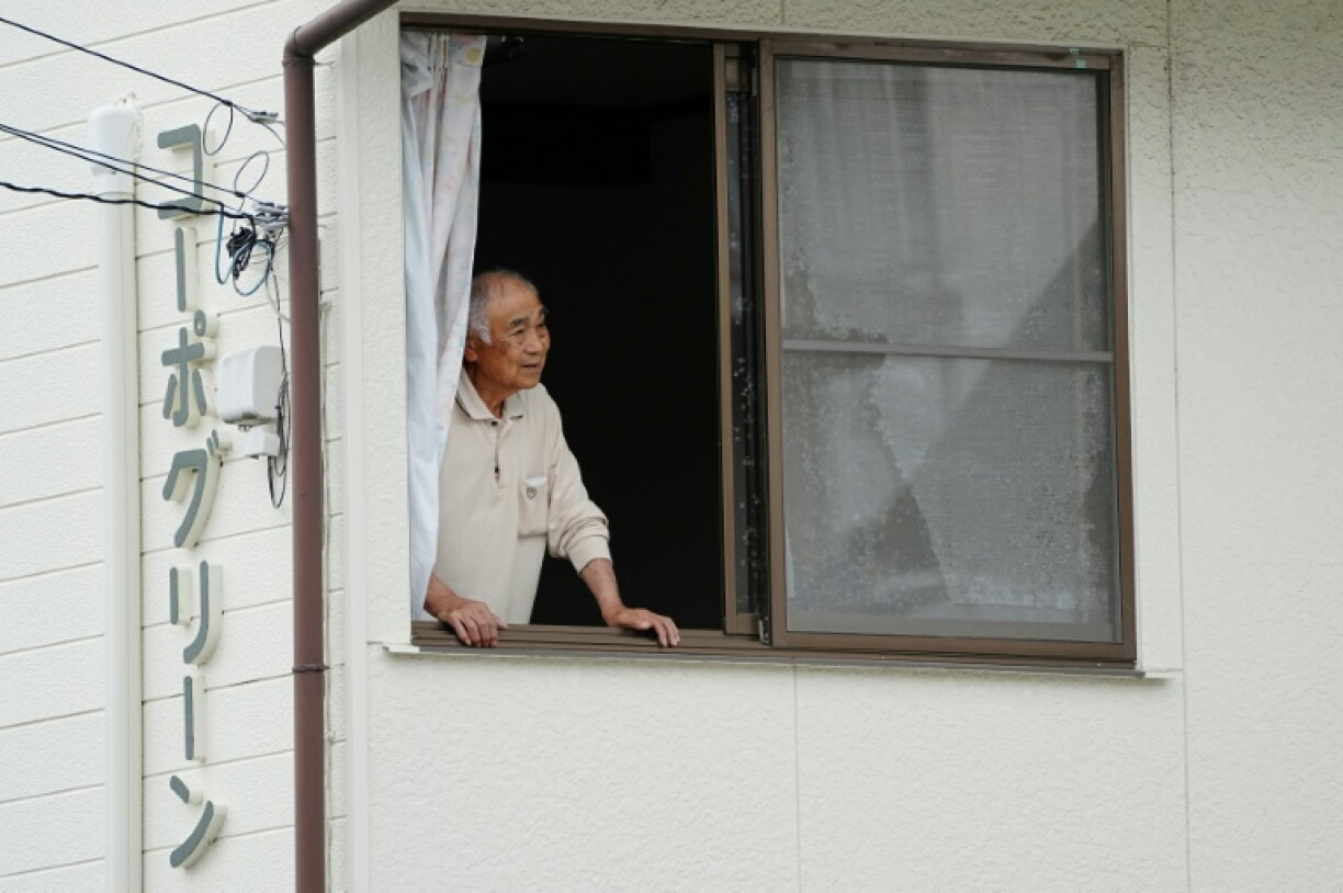 Un habitant regarde depuis sa maison des chasseurs et personnels d'un zoo à la recherche d'un ours sauvage dans la ville de Utsunomiya, au nord de Tokyo, le 9 juin 2026