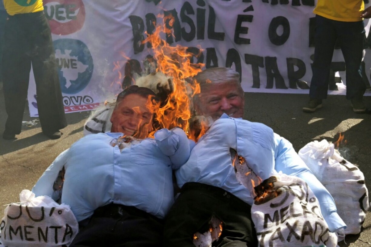Dummies depicting US President Donald Trump (R) and Brazil's former President Jair Bolsonaro are burnt during a pro-national sovereignty protest following the US imposition of trade taxes and sanctions