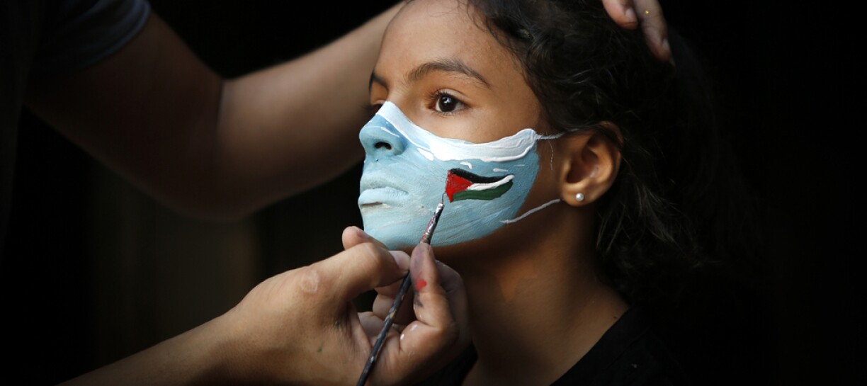 A Palestinian artist draws a face mask on a child to create awareness about ways to prevent the spread of the Covid-19 coronavirus, in Gaza City on September 8, 2020.