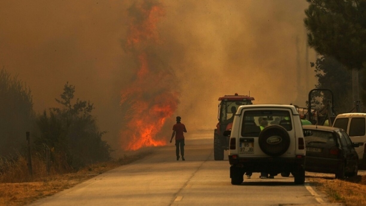Un homme se dirige vers les flammes sur une route couverte de fumée dans le village d'Antas au Portugal, le 15 août 2025