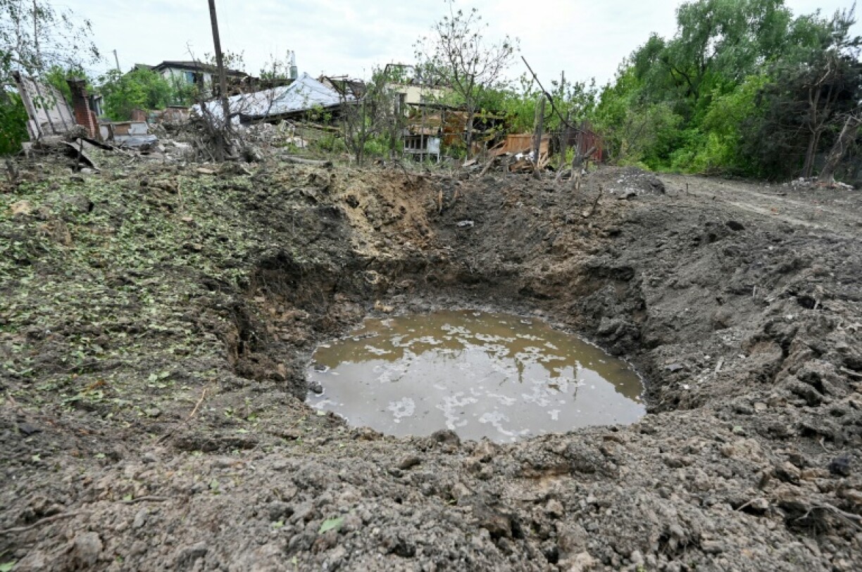 Un cratère devant une maison détruite par une frappe, le 22 mai 2023 à Tsirkuny, dans la région de Kharkiv, en Ukraine