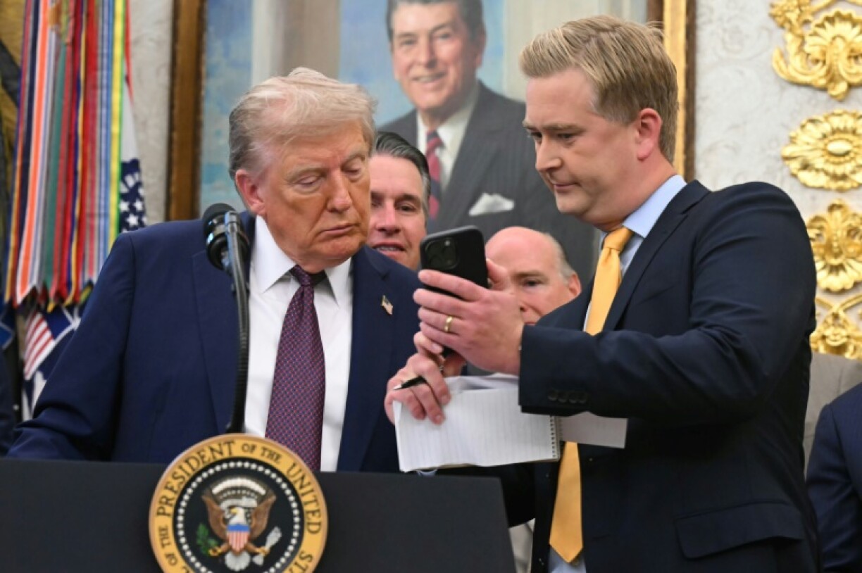 Fox News reporter Peter Doocy shows US President Donald Trump his phone during an Oval Office press conference