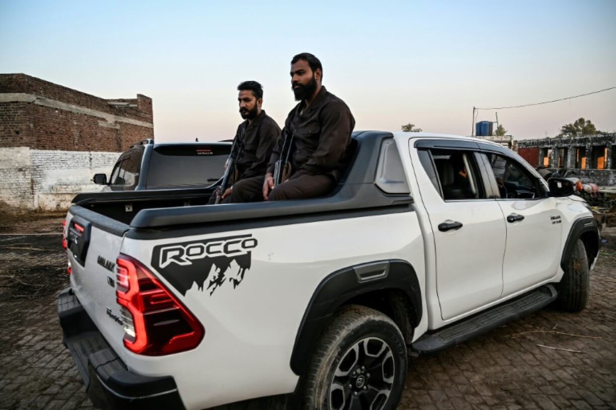 Armed security guards sit in the back of a Hilux used by politician Ali Warraich, who says an escort of two of the popular trucks is essential
