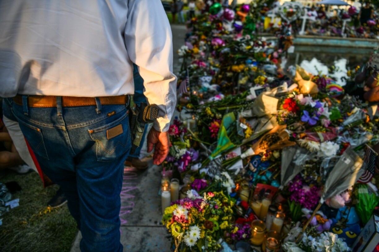 Un homme armé devant un mémorial en hommage aux victimes de la tuerie d'Uvalde.