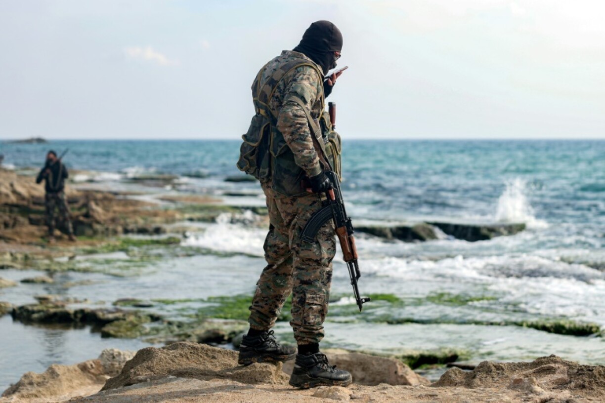 A member of security forces loyal to the interim Syrian government speaks on a cell phone along the Mediterranean Sea in Syria' Latakia