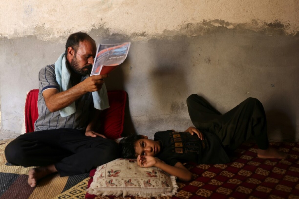 An Iraqi man fans his son at his home south of Hilla amid the heat of August