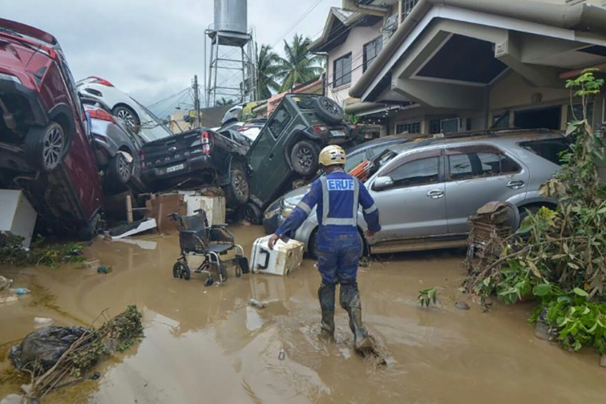 A rescuer walks past piled up cars washed away by floods at the height of Typhoon Kalmaegi in a subdivision of Cebu City