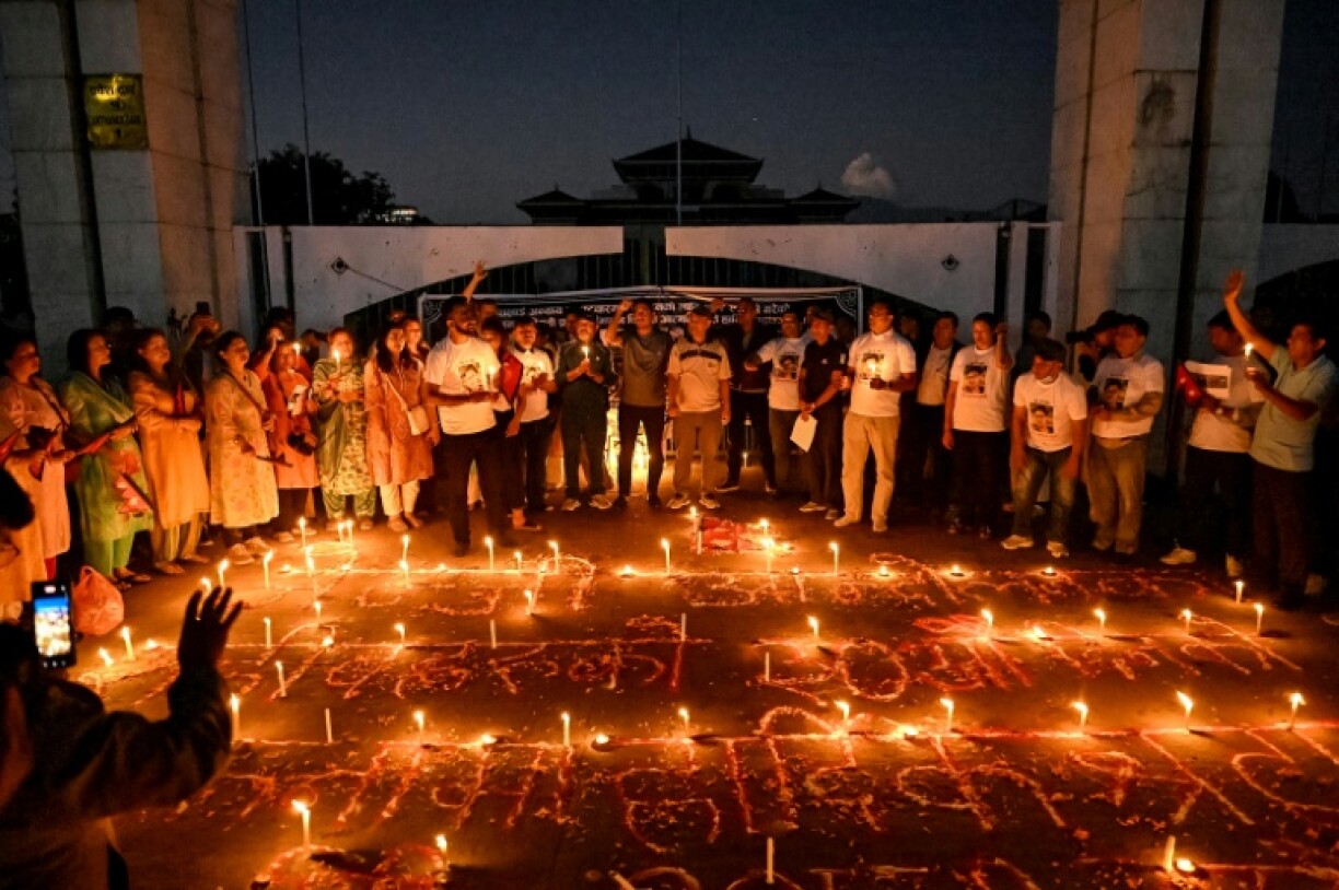 Nepalis lit candles outside the fire-damaged parliament building on Thursday, one month after anti-corruption protests toppled the government and left dozens dead