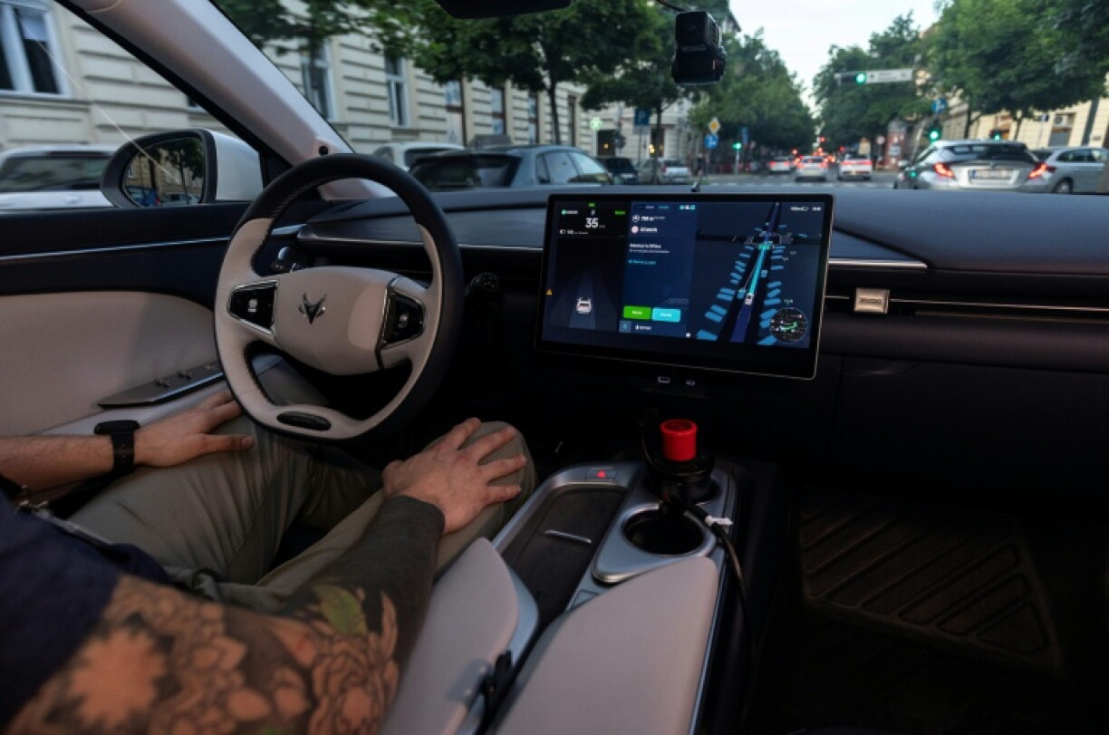 Le volant et l'écran de contrôle d'un robotaxi Verne à Zagreb, en Croatie, avec un opérateur de sécurité mains sur les genoux, le 4 mai 2026
