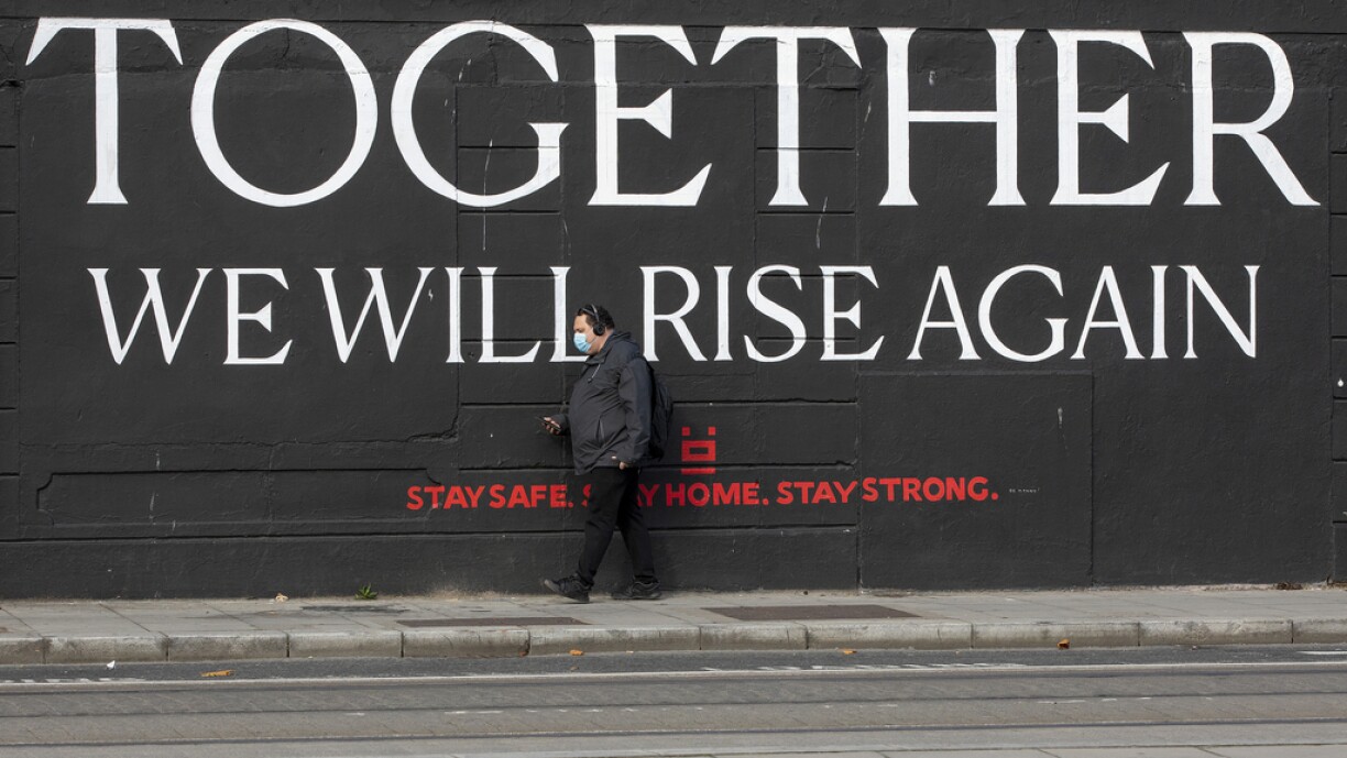 A man wearing a face mask as a precaution against the transmission of the novel coronavirus walks past a mural in Dublin on October 21, 2020 as Ireland prepares to enter a second national lockdown to stem the spread of the virus that causes Covid-19.