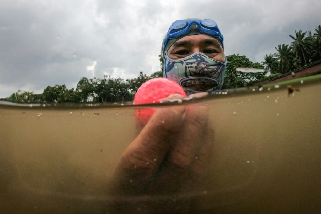 Retired navy frogman Sumadi Ibrahim, 51, with a golf ball he found in a pond at a course in Shah Alam, on the outskirts of Kuala Lumpur