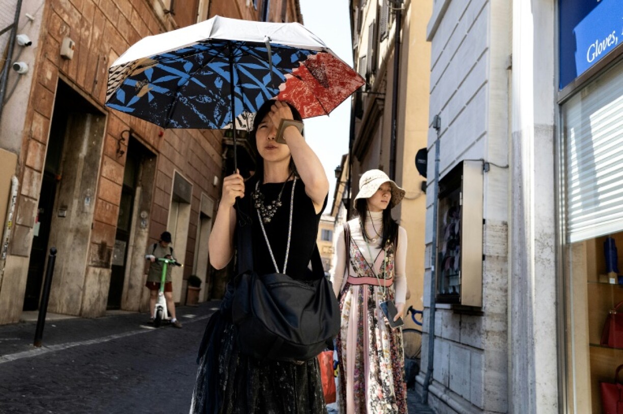 A tourist in Rome holds an umbrella to protect herself from the sun
