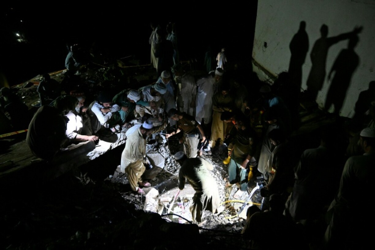 Rescue workers and residents search for victims in the debris of collapsed houses after a cloudburst in Dolari village, in northern Pakistan