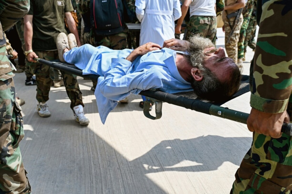 Taliban security personnel carry an Afghan earthquake victim evacuated by a military helicopter