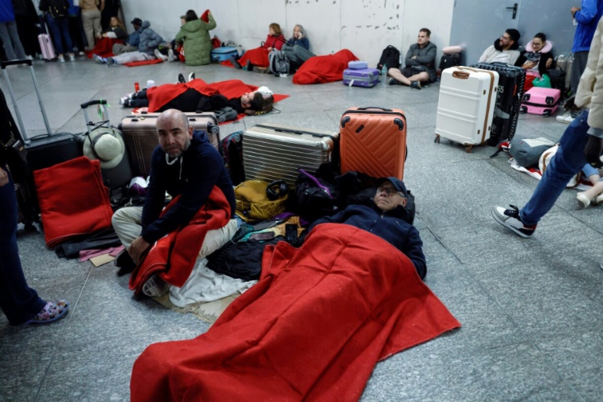 Travellers with Red Cross blankets lie prepare to spend the night at Madrid's Atocha train station