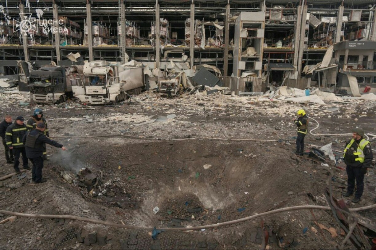 Ukrainian law enforcement officers inspect a crater at the site of an air attack in Kyiv