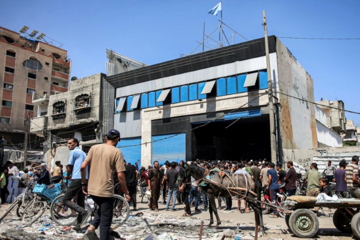 Des personnes sont rassemblées à l'extérieur d'un entrepôt espérant recevoir un paquet d'aide humanitaire de l'agence de l'ONU pour les réfugiés palestiniens (Unrwa) dans le centre de la ville de Gaza le 27 août 2024