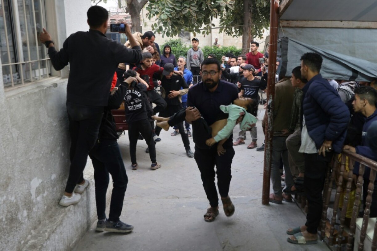 A Palestinian man carries an injured girl to al-Ahli hospital in Gaza City on 6 April 2025.